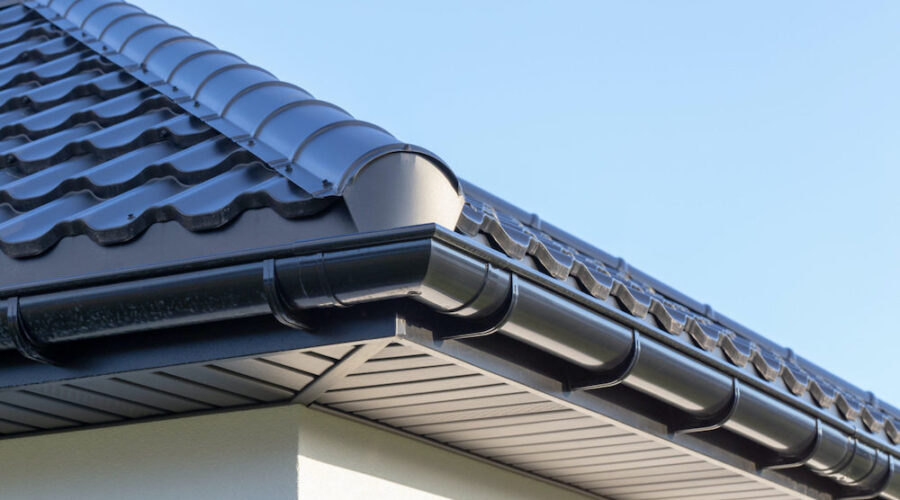 Corner of the new modern house with gutter, roof, wall under blue sky